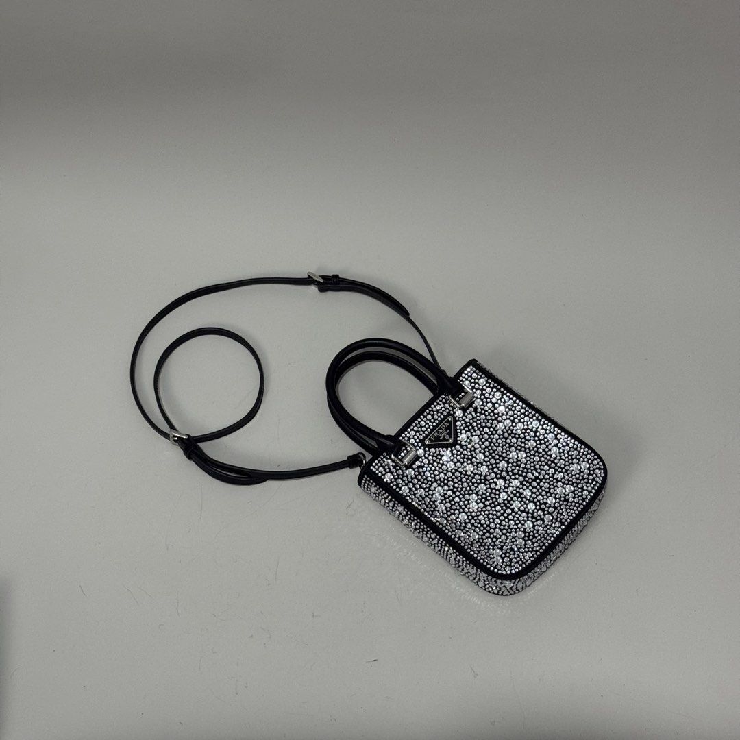 Prada Mini Handbag with Embellishments (Category: Luxury Bags & Wallets) located in Dagupan City. Submitted by thriftygoods.dagupan (Listing ID 1439609323, Image 3). Description: Prada mini handbag features a black leather exterior fully embellished with silver-toned studs. It has a top handle and a detachable shoulder strap. The interior includes a Prada logo plaque. Made in Italy..