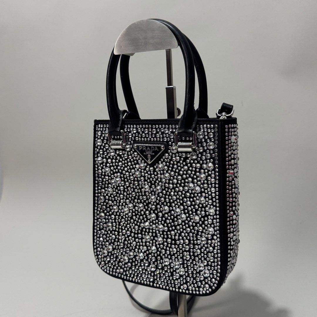 Prada Mini Handbag with Embellishments (Category: Luxury Bags & Wallets) located in Dagupan City. Submitted by thriftygoods.dagupan (Listing ID 1439609323, Image 2). Description: Prada mini handbag features a black leather exterior fully embellished with silver-toned studs. It has a top handle and a detachable shoulder strap. The interior includes a Prada logo plaque. Made in Italy..
