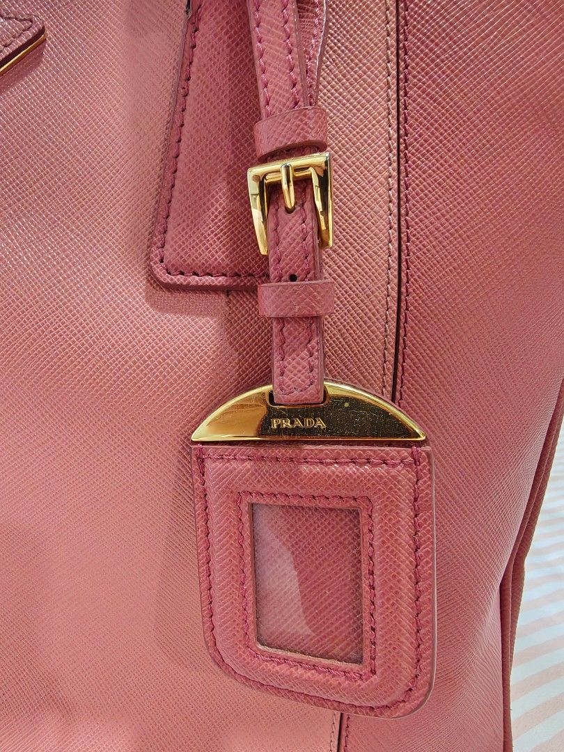 Prada Saffiano Leather Tote Bag (Category: Luxury Bags & Wallets) located in Pasay City. Submitted by autumn35 (Listing ID 1439694737, Image 3). Description: - Authentic Prada tote bag - Dual-tone pink Saffiano leather exterior - Gold-tone hardware - Double top handles - Detachable luggage tag - Zip closure - Lined interior - Prada logo on front - No dust bag included - Strap included - dm me for more photos including the flaws...