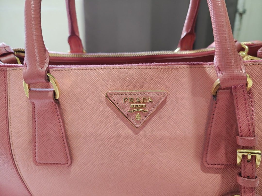 Prada Saffiano Leather Tote Bag (Category: Luxury Bags & Wallets) located in Pasay City. Submitted by autumn35 (Listing ID 1439694737, Image 2). Description: - Authentic Prada tote bag - Dual-tone pink Saffiano leather exterior - Gold-tone hardware - Double top handles - Detachable luggage tag - Zip closure - Lined interior - Prada logo on front - No dust bag included - Strap included - dm me for more photos including the flaws...
