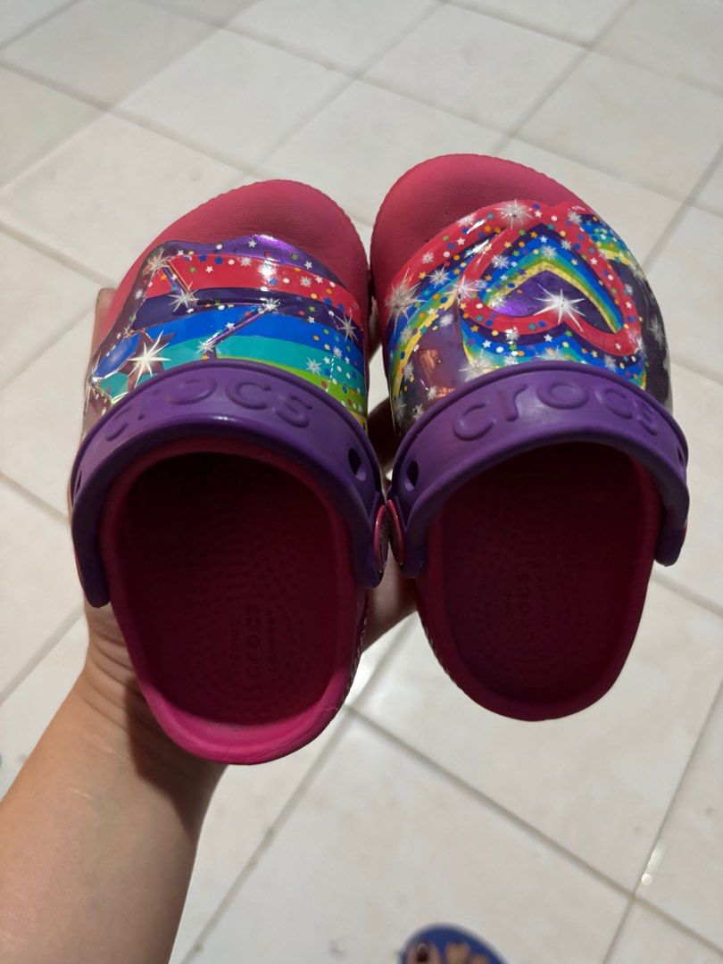 Preloved Crocs Kids Size C5 w/lights (Category: Babies & Kids Fashion) located in Malabon City. Submitted by kwisteyndg (Listing ID 1439614106, Image 1). Description: - Pink Crocs clogs for kids - Size: C5 - Features a purple strap - Colorful design on top - Visible Crocs logo - Soles show wear.