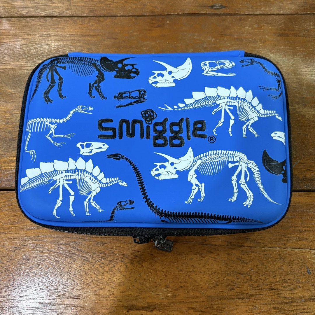 Smiggle Dinosaur Pencil Case (Category: Stationery & School Supplies) located in Las Pinas. Submitted by kapkards (Listing ID 1439727417, Image 1). Description: - Smiggle pencil case with a cool dinosaur skeleton design. - Features a blue exterior and a black zipper. - Includes a mesh pocket for storage. - Has a flap with slots for pens and pencils. - Spacious design, perfect for organizing school supplies..