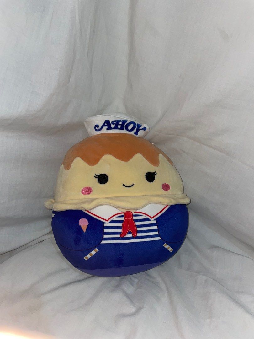 Squishmallows Stranger Things Robin Plush (Category: Plushies & Soft Toys) located in Manila. Submitted by mightylion.aa32e0 (Listing ID 1439745928, Image 1). Description: - Squishmallows Robin plush from Stranger Things. - Features a blue sailor outfit with a red stripe. - Includes a white sailor hat that says "AHoy". - Soft and round design. - Comes with a "Stranger Things Netflix" tag..