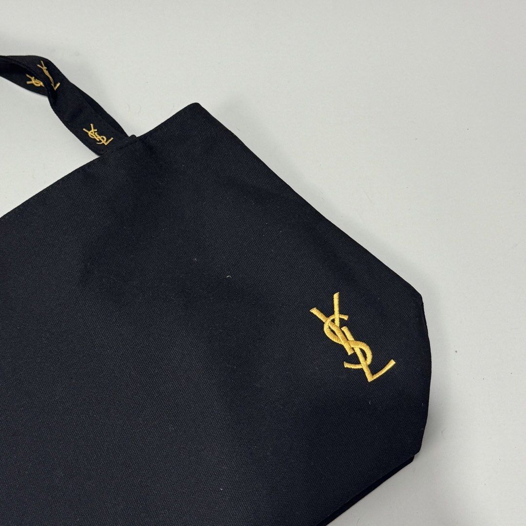 Yves Saint Laurent Black Tote Bag (Category: Luxury Bags & Wallets) located in Dagupan City. Submitted by thriftygoods.dagupan (Listing ID 1439609468, Image 3). Description: - Authentic Yves Saint Laurent tote bag - Classic black color - Gold YSL logo on front and zipper - YSL logo on handles - Pink interior lining - Interior zippered pocket with YSL logo - Secure zipper closure.