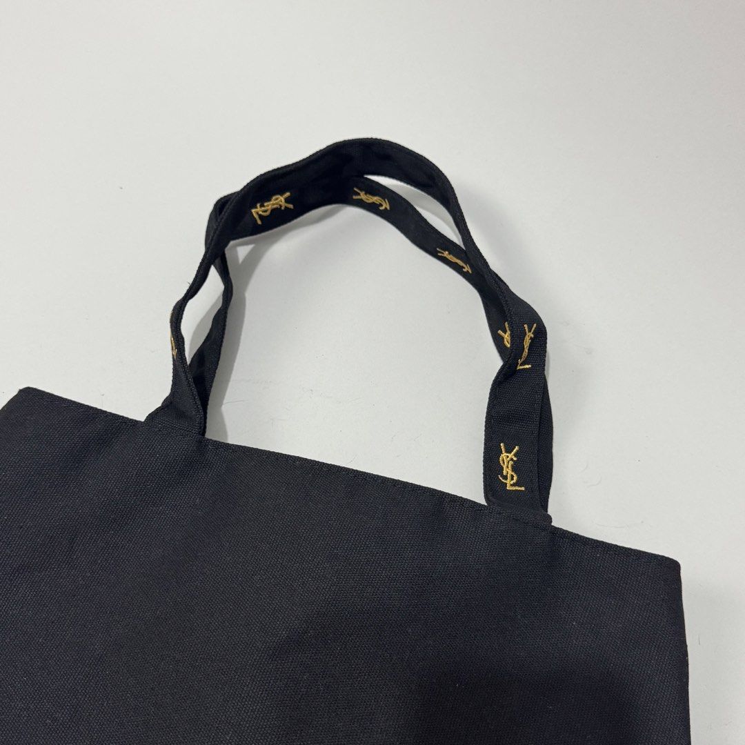 Yves Saint Laurent Black Tote Bag (Category: Luxury Bags & Wallets) located in Dagupan City. Submitted by thriftygoods.dagupan (Listing ID 1439609468, Image 2). Description: - Authentic Yves Saint Laurent tote bag - Classic black color - Gold YSL logo on front and zipper - YSL logo on handles - Pink interior lining - Interior zippered pocket with YSL logo - Secure zipper closure.