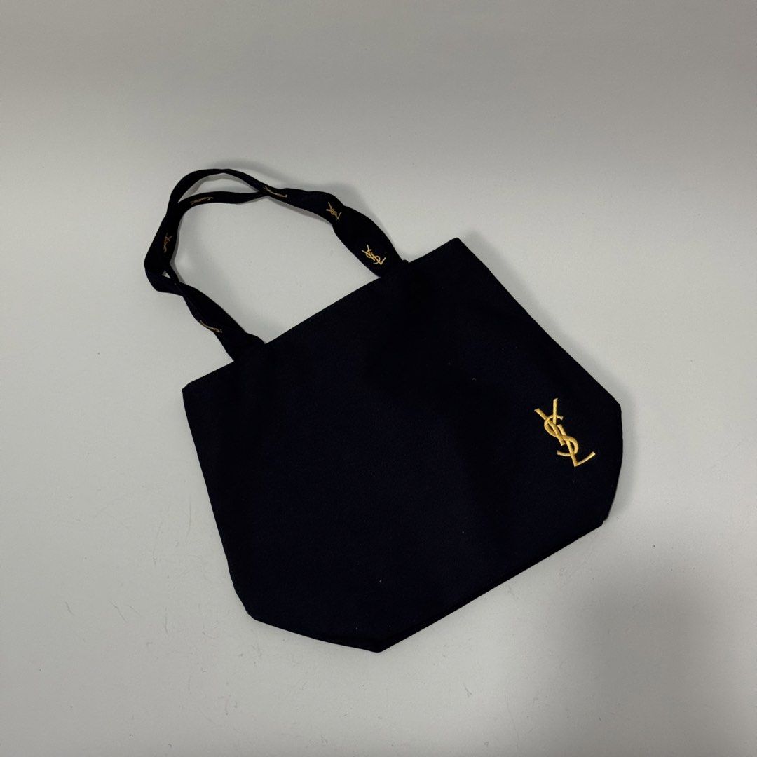 Yves Saint Laurent Black Tote Bag (Category: Luxury Bags & Wallets) located in Dagupan City. Submitted by thriftygoods.dagupan (Listing ID 1439609468, Image 1). Description: - Authentic Yves Saint Laurent tote bag - Classic black color - Gold YSL logo on front and zipper - YSL logo on handles - Pink interior lining - Interior zippered pocket with YSL logo - Secure zipper closure.