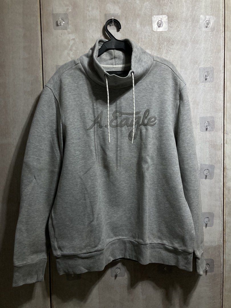 American Eagle Grey Mock Neck Sweatshirt (Category: Coats, Jackets and Outerwear) located in Iloilo. Submitted by __kyleeee__ (Listing ID 1439918743, Image 1). Description: - Grey American Eagle sweatshirt - Mock neck with drawstring detail - Embroidered 'A. Eagle' logo on front - Long sleeves - Ribbed cuffs and hem - Ideal for casual wear.