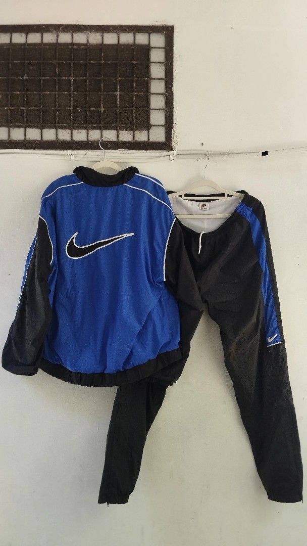 Nike Tracksuit - Blue and Black (Category: Sets & Coordinates) located in Manila. Submitted by izla.thrift (Listing ID 1439834671, Image 1). Description: - Nike blue and black tracksuit. - Jacket features: - Large Nike swoosh logo on the back. - Blue body with black sleeves and white trim. - Matching black pants with blue side stripe and Nike logo. - Made of lightweight material..