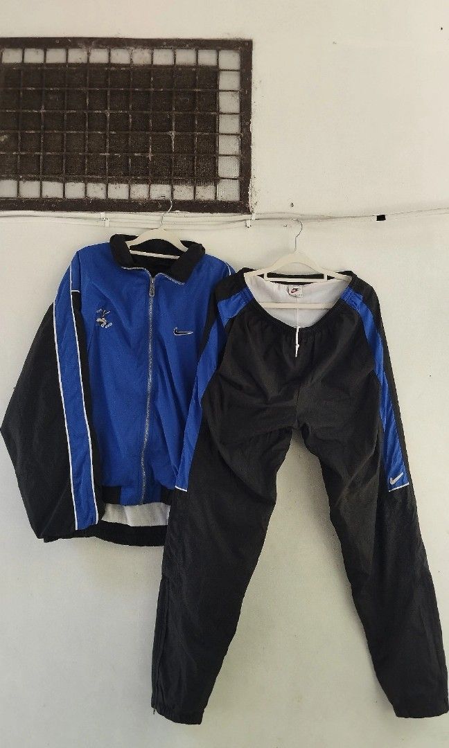 Nike Tracksuit - Blue and Black (Category: Sets & Coordinates) located in Manila. Submitted by izla.thrift (Listing ID 1439834671, Image 2). Description: - Nike blue and black tracksuit. - Jacket features: - Large Nike swoosh logo on the back. - Blue body with black sleeves and white trim. - Matching black pants with blue side stripe and Nike logo. - Made of lightweight material..