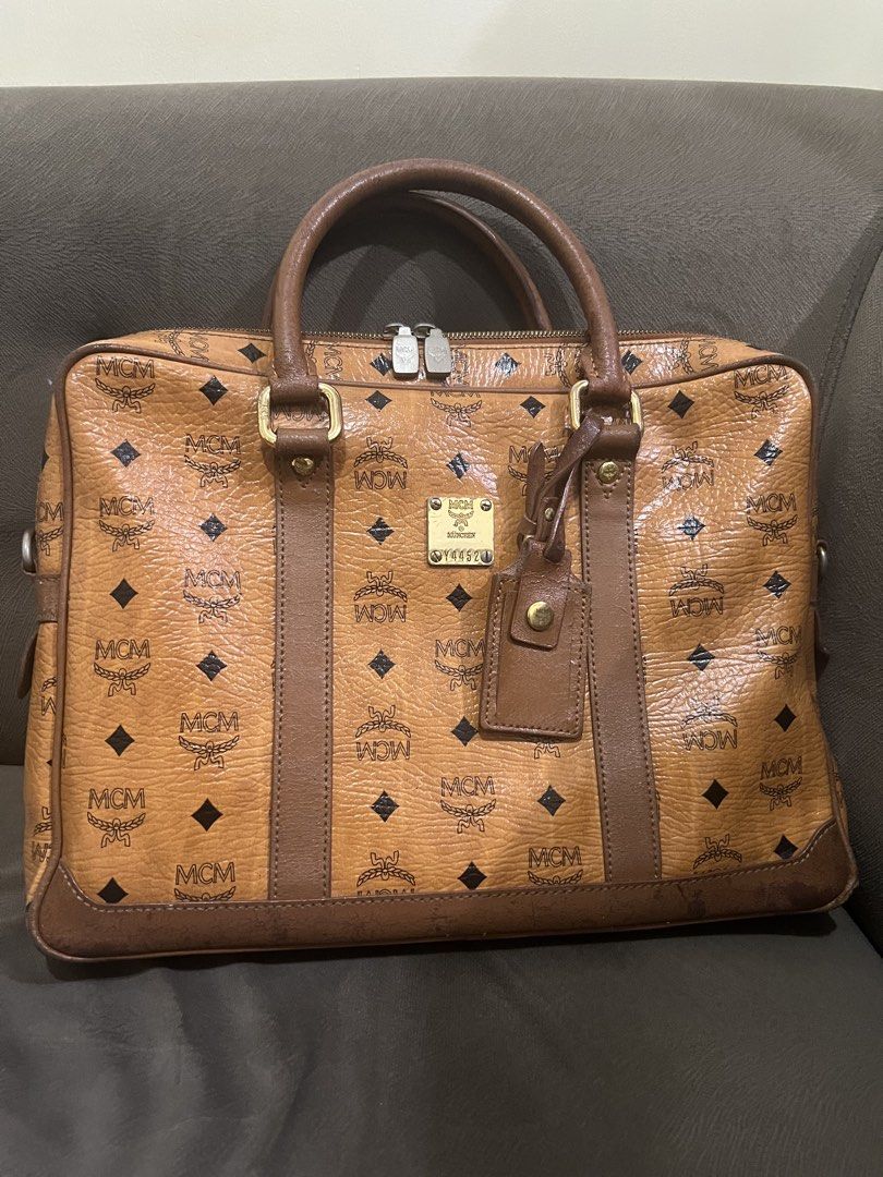 Authentic MCM Cognac Laptop/Document Bag (Category: Luxury Bags & Wallets) located in Manila. Submitted by sanyatagle08878 (Listing ID 1440089684, Image 1). Description: - Authentic MCM Cognac Laptop/Document Bag - Can fit 13-inch laptop - Turnable screws - Gold MCM logo plate on front Issues: Please check the photos posted. Some issues are labas piping, bag handle scratches and in some part of the bags. Location: La Loma, QC RFS: decluttering so