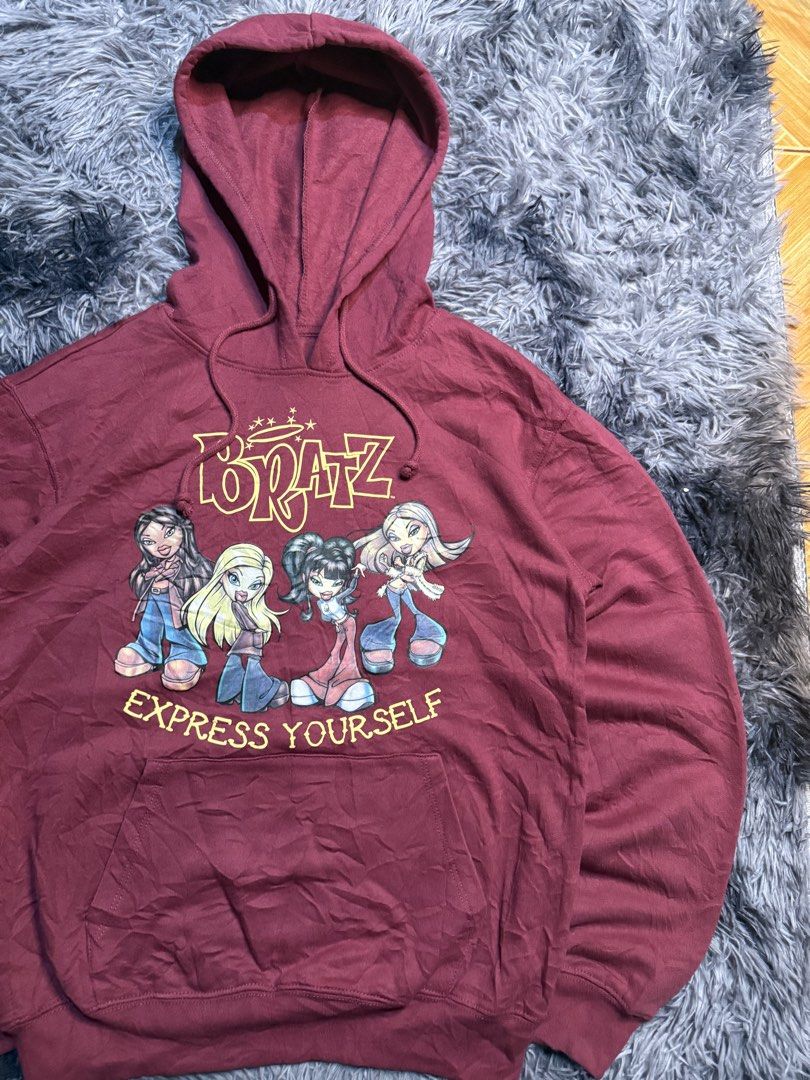 Bratz "Express Yourself" Graphic Hoodie (Category: Hoodies) located in San Marcelino. Submitted by SoloMain (Listing ID 1440165581, Image 2). Description: - Cozy maroon hoodie featuring classic Bratz characters - "Express Yourself" slogan adds a fun touch - Comfortable cotton-polyester blend fabric - Convenient front pocket for essentials - Perfect for any Bratz doll enthusiast - 19 by 24.