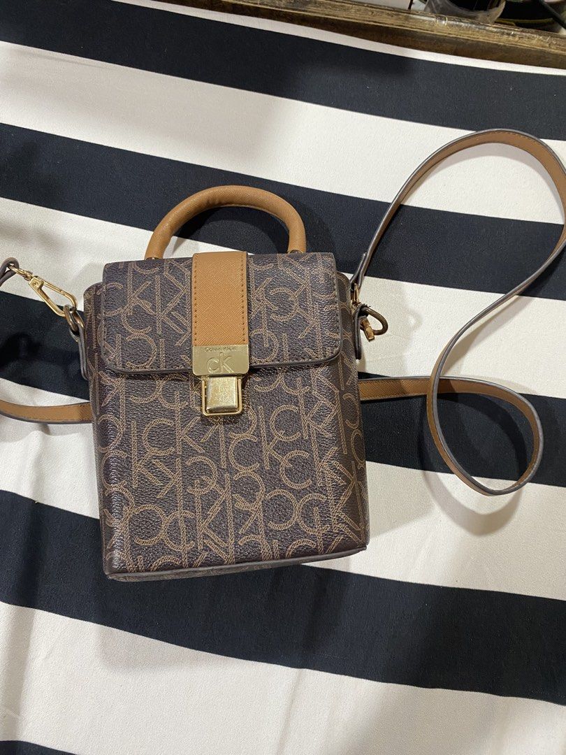 Calvin Klein Monogram Box Bag with Strap (Category: Luxury Bags & Wallets) located in Bulacan. Submitted by pmlsg (Listing ID 1440033410, Image 1). Description: - Stylish Calvin Klein box bag - Signature monogram print - Top handle - Detachable crossbody strap for versatile carrying - Lined interior with compartments - Secure gold-tone clasp closure.