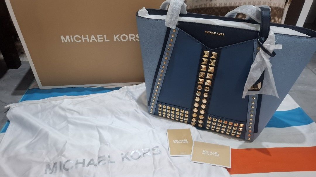 Michael Kors Studded Tote Bag (Category: Luxury Bags & Wallets) located in Trece Martires City. Submitted by lotlotonlineshop (Listing ID 1440074787, Image 2). Description: - Authentic Michael Kors tote bag - Stylish blue and navy color block design - Gold-tone stud embellishments on front and sides - Comes with original dust bag and box - Perfect for everyday use or a night out.