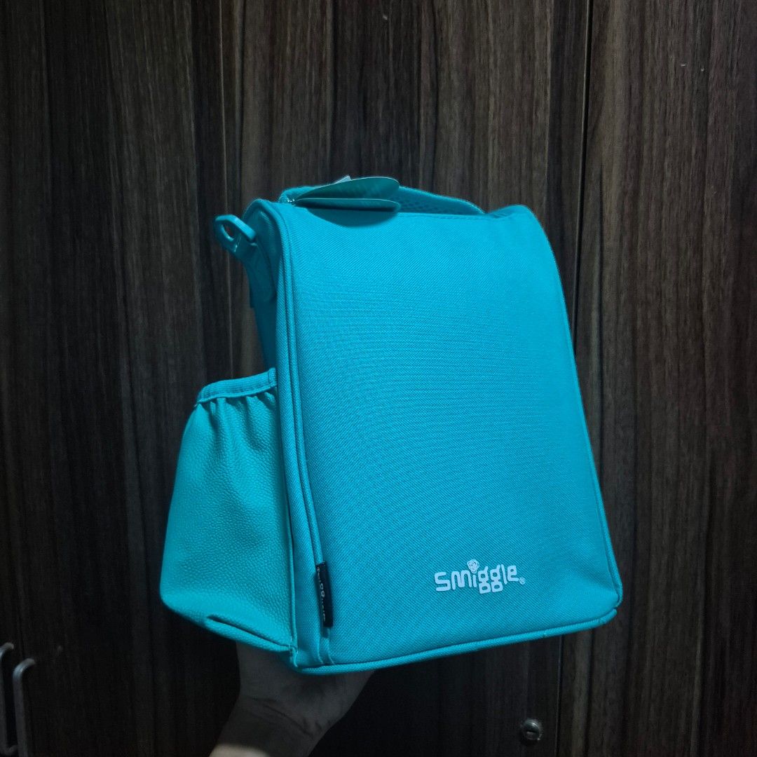 Smiggle Teal Blue Dinosaur Printed Lunch Bag (Category: Other Babies Going Out Needs) located in Manila. Submitted by mho.marie (Listing ID 1440100946, Image 2). Description: Original smiggle (bought in actual smiggle store overseas) Brandnew, never been used insulated lunch bag with sling Can put a lot of items inside if bought with lunch box & sip bottle (please other listings) cab give discount .
