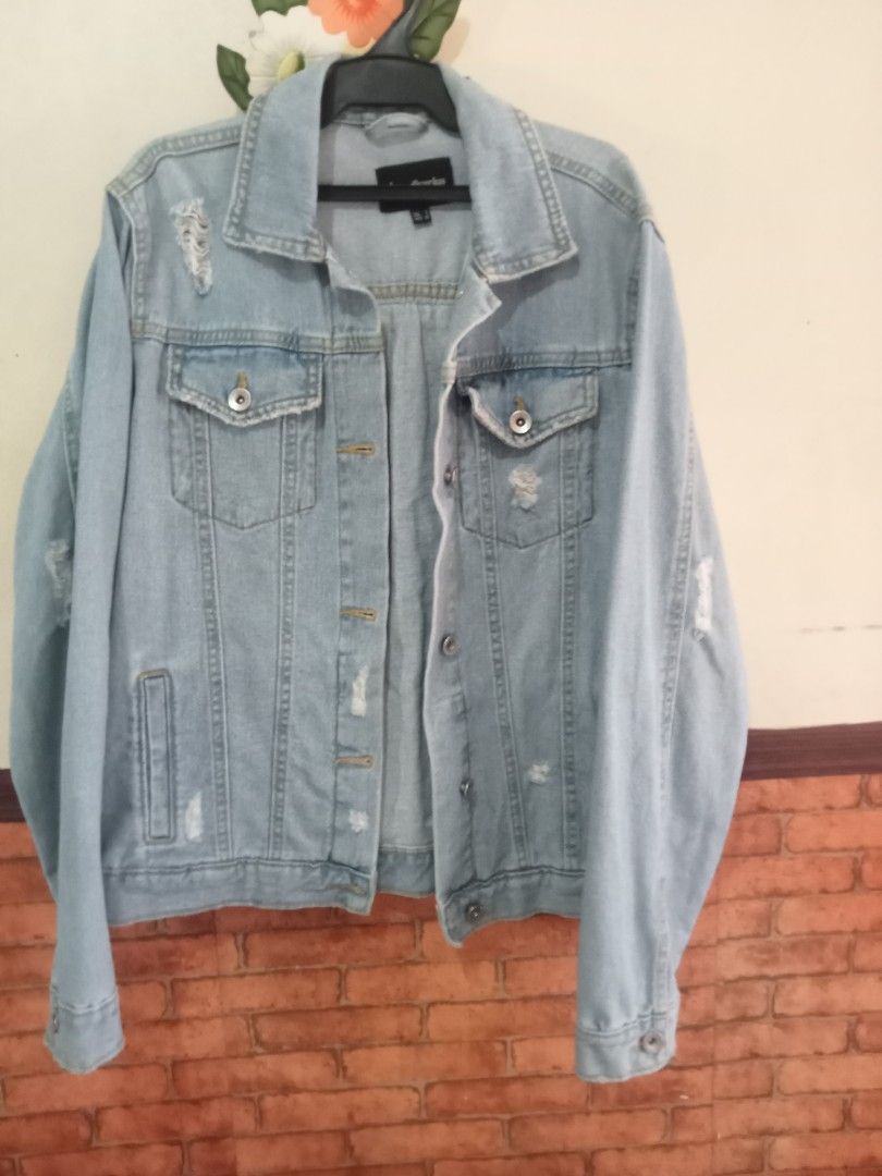 Stradivarius Denim Jacket with Embroidered Back (Category: Coats, Jackets and Outerwear) located in Paete. Submitted by glamluxxereloved (Listing ID 1440031586, Image 1). Description: S on tag but can fit Medium Pre-loved not ukay - Stradivarius light wash denim jacket - Distressed details on sleeves - Unique embroidered tribal-inspired design on back - Classic button-up front - Chest pockets - Adds a stylish edge to any outfit Vguc needs wash ka