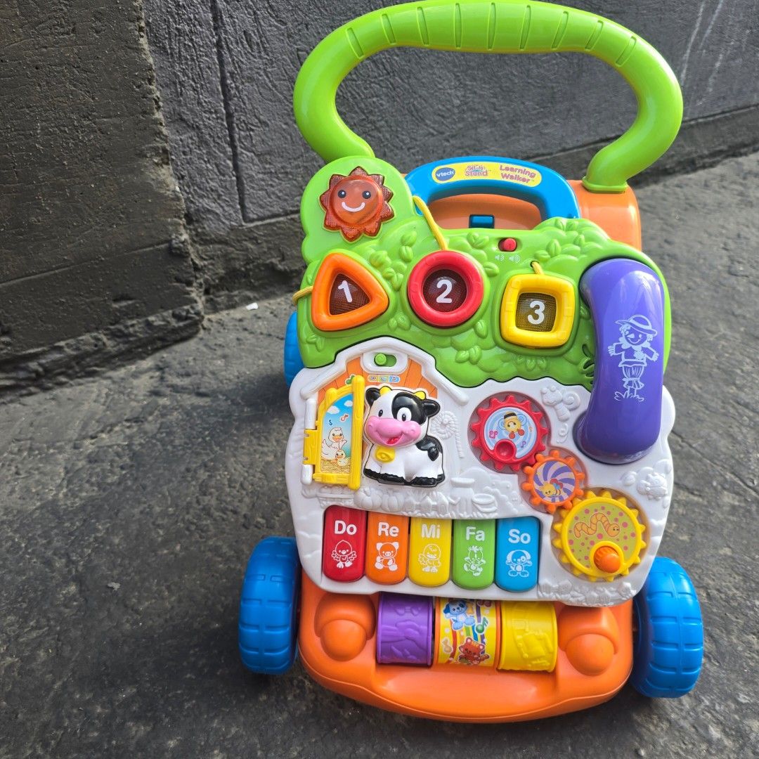 VTech Sit-to-Stand Learning Walker Toy (Category: Infant Playtime) located in Marikina City. Submitted by grcpw (Listing ID 1440133553, Image 1). Description: VTech Sit-to-Stand Learning Walker - helps baby learn to walk and play! Features music, gears, numbers, and a cow. Green handle for support. Bright colors. Wheels are flawless as seen in photos! location Marikina.