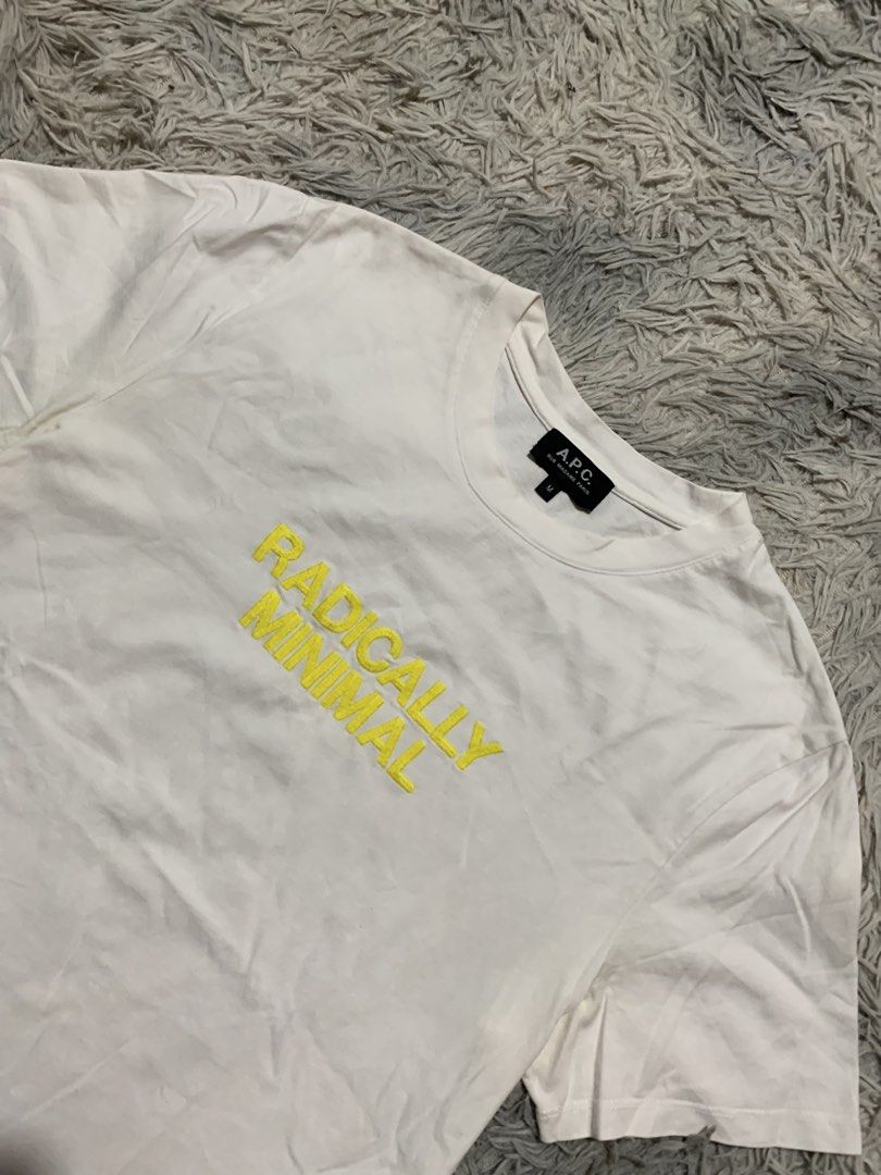 A.P.C. "Radically Minimal" T-Shirt Size M (Category: Tshirts & Polo Shirts ) located in Cebu City. Submitted by ninyothrift (Listing ID 1440344877, Image 2). Description: - Brand: A.P.C. - Color: White - Size: M - Design: Crew neck, short sleeves - Embroidery: 'RADICALLY MINIMAL' in yellow on the chest - Logo: Subtle A.P.C. logo embroidered on the sleeve - Origin: Made in Portugal - Style: Classic, minimalist staple piece - 21x27 - Excellent cond
