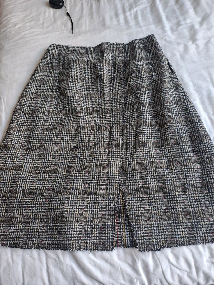 BREAD AND BUTTER TWEED SKIRT (Category: Skirts) located in Manila. Submitted by joanbalde39643 (Listing ID 1440280627, Image 1). Description: The item shown in the image is a plaid tweed skirt featuring a black waistband lining and an inner brand tag from the clothing label bread n butter. The garment is styled with a classic, multi-colored speckled tweed pattern (featuring hints of red, blue, and yellow) and is equipped with a smooth inner fabri