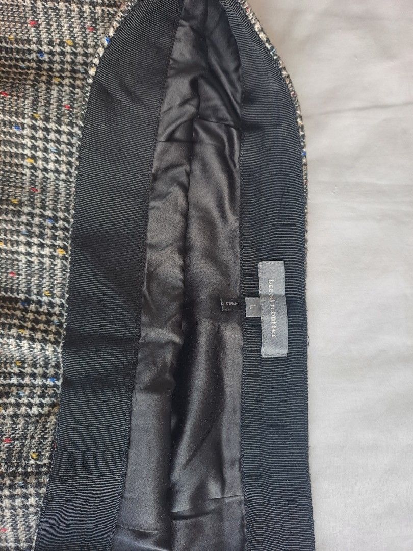 BREAD AND BUTTER TWEED SKIRT (Category: Skirts) located in Manila. Submitted by joanbalde39643 (Listing ID 1440280627, Image 3). Description: The item shown in the image is a plaid tweed skirt featuring a black waistband lining and an inner brand tag from the clothing label bread n butter. The garment is styled with a classic, multi-colored speckled tweed pattern (featuring hints of red, blue, and yellow) and is equipped with a smooth inner fabri