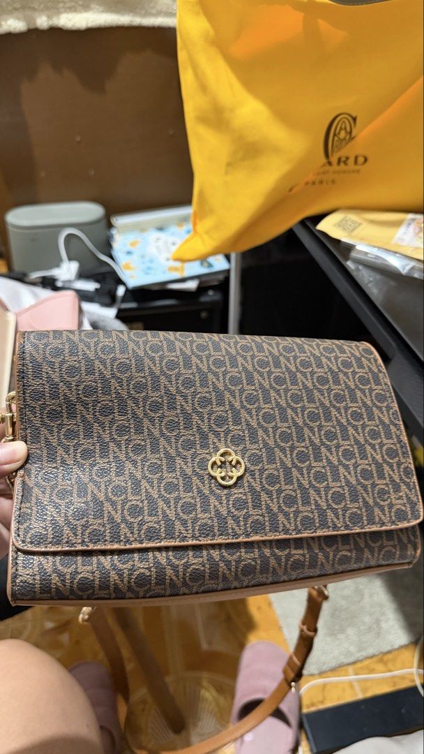 Brown Monogram Clutch Bag with Gold Chain Strap (Category: Clutches) located in Manila. Submitted by wisewind_6fa49c (Listing ID 1440236100, Image 1). Description: - Stylish brown clutch bag - Repeating monogram pattern - Gold-tone logo emblem - Secure snap closure - Spacious interior with zippered pocket - Detachable gold chain and leather strap - Versatile carrying options - Perfect for evenings out or adding elegance.