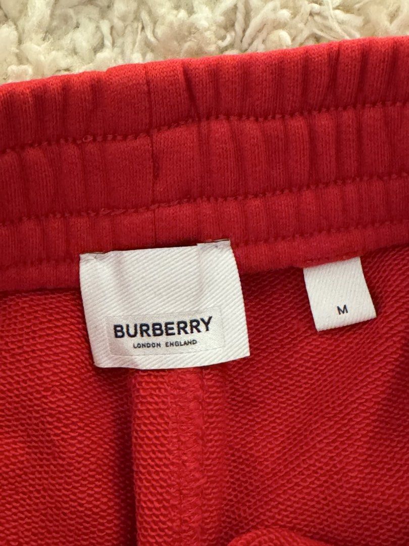 Burberry Red Sweatpants Joggers Size M (Category: Joggers) located in San Nicolas. Submitted by ihascat (Listing ID 1440344037, Image 2). Description: - Authentic Burberry sweatpants - Iconic TB logo on left thigh - Elastic waistband with drawstring - Ribbed cuffs - Size M - Ideal for casual wear.