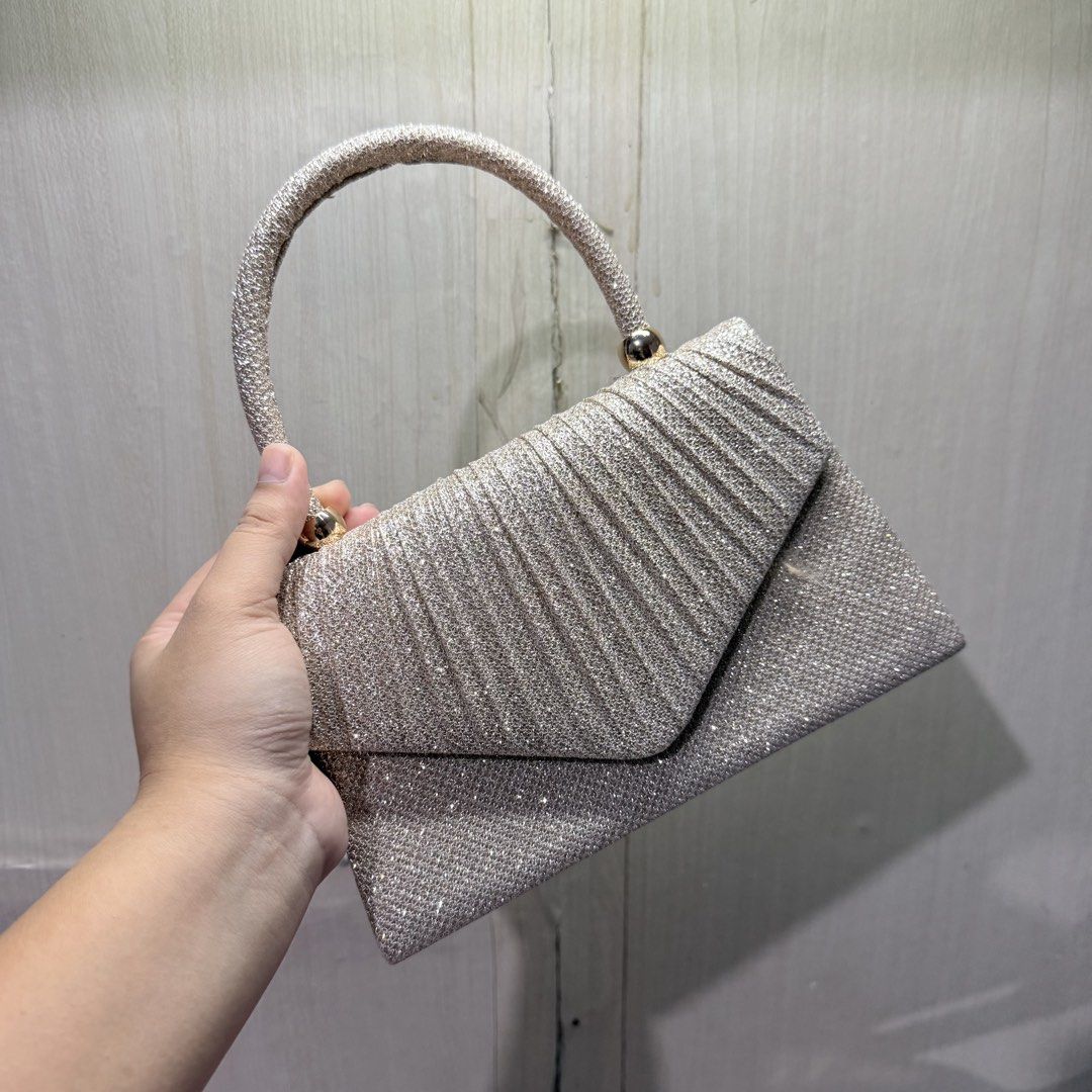 Champagne Classy Sling Bag with Handle (Category: Clutches) located in Tarlac. Submitted by milkshakeee_ (Listing ID 1440276041, Image 2). Description: - Never been used (BRAND NEW) - Bought at tiktok - Champagne sparkly clutch bag - Convenient short handle - Secure magnetic snap closure - Includes a small inner pocket - Ideal for parties, events, and special occasions - Fits essentials like your phone, keys, and lipstick.