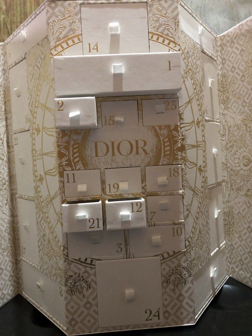 Dior CD Logo Advent Calendar Box (Category: Makeup) located in Montevista. Submitted by rdthriftshub (Listing ID 1440198863, Image 2). Description: - Authentic Dior Advent Calendar - Features a beautiful gold CD logo on the front - Elegant white design with intricate gold patterns - 25 numbered drawers for a daily festive countdown - Opens to reveal individual compartments.