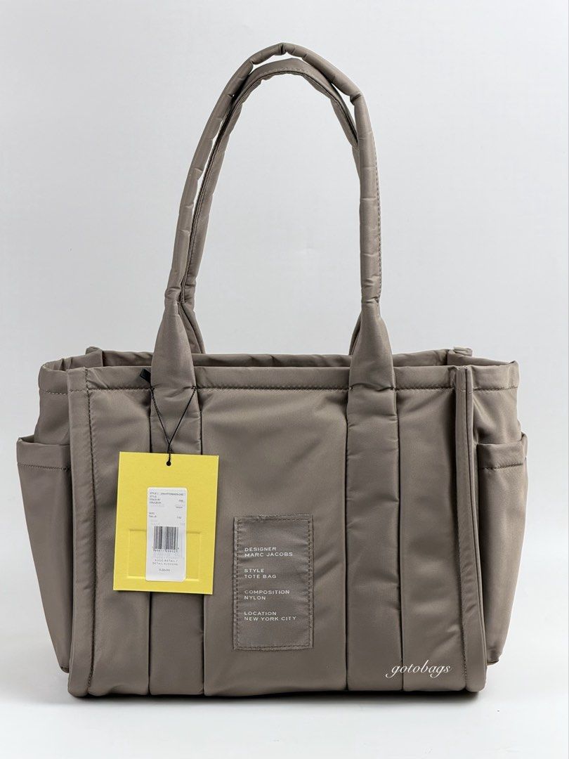 Marc Jacobs The Tote Bag Medium Nylon Silver (Category: Luxury Bags & Wallets) located in Angeles City. Submitted by gobagsto (Listing ID 1440282336, Image 3). Description: - Medium size Marc Jacobs nylon tote bag - CEMENT - Signature 'The Tote Bag' embroidered logo on front - Top handles - Detachable shoulder strap with 'The Tote Bag' text - Multiple exterior pockets for easy access - Interior zip pocket - Bright orange lining.