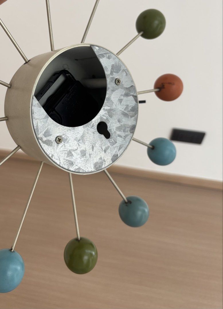 Mid-Century Modern Style Ball Clock (Category: Clocks) located in Mandaluyong City. Submitted by shopjp33 (Listing ID 1440250657, Image 3). Description: Herman Miller replica ball clock Add a touch of retro charm to your space with this unique wall clock. Featuring a cream-colored center and a dynamic arrangement of colorful balls (teal, black, green, and orange) on metal spokes, it's a true statement piece. The clock has black hour and minute ha