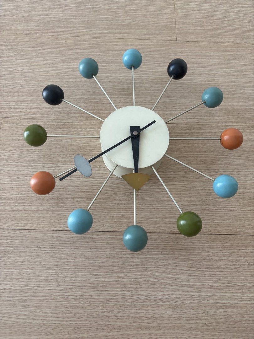 Mid-Century Modern Style Ball Clock (Category: Clocks) located in Mandaluyong City. Submitted by shopjp33 (Listing ID 1440250657, Image 2). Description: Herman Miller replica ball clock Add a touch of retro charm to your space with this unique wall clock. Featuring a cream-colored center and a dynamic arrangement of colorful balls (teal, black, green, and orange) on metal spokes, it's a true statement piece. The clock has black hour and minute ha