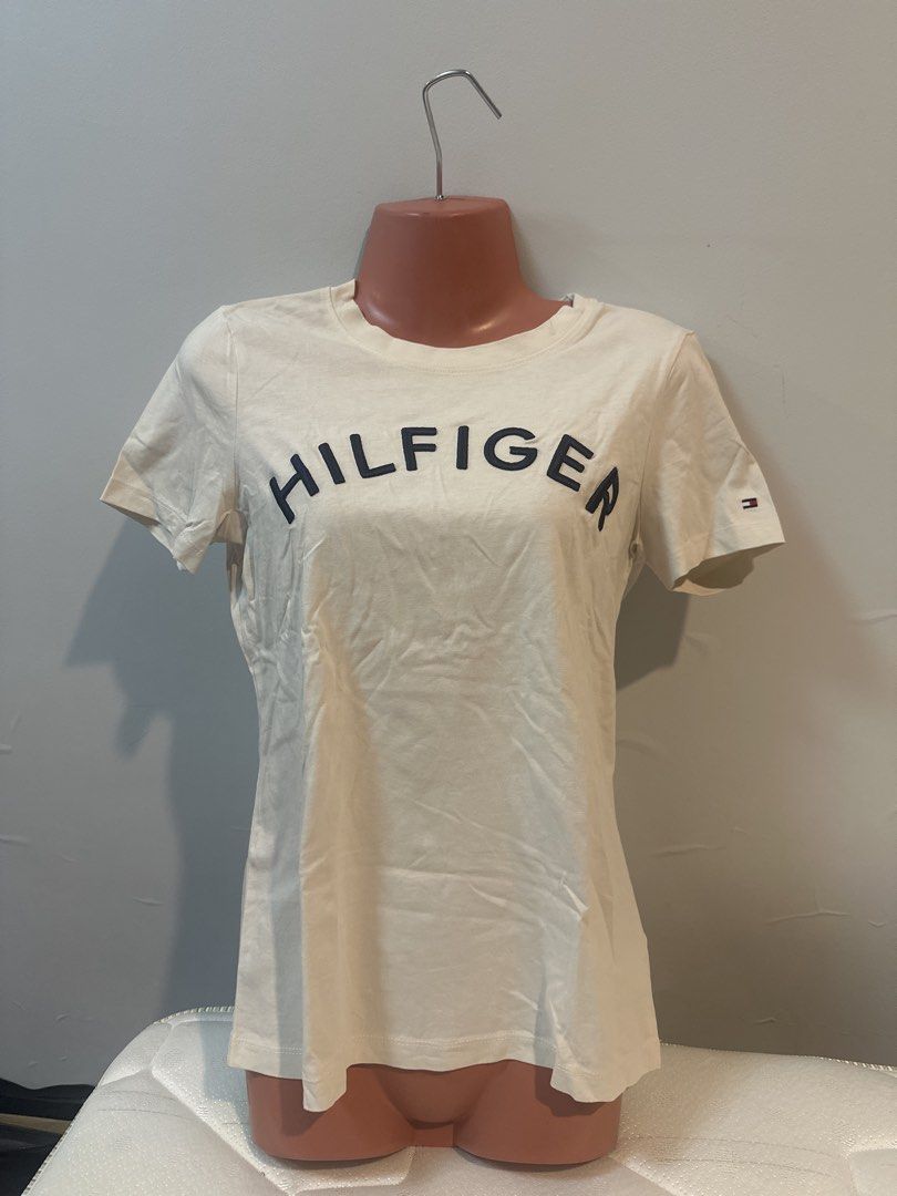 Tommy Hilfiger T-shirt (Category: Shirts) located in Las Pinas. Submitted by Mkdot (Listing ID 1439831762, Image 1). Description: - Cream-colored Tommy Hilfiger T-shirt - Crew neck - Navy blue Tommy Hilfiger logo on chest - Short sleeves - Plain back - Lightweight fabric - Perfect for everyday wear - A versatile wardrobe staple.