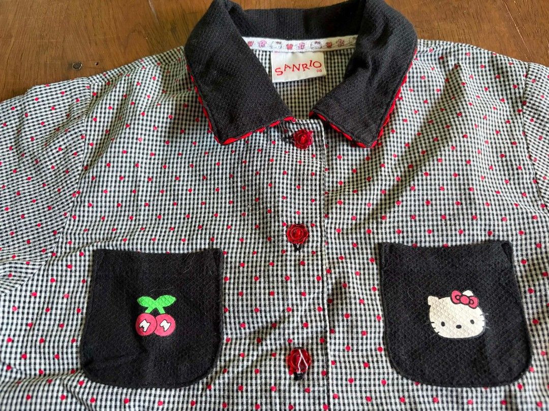 Vintage Sanrio (Hello Kitty Cherry Plaid) (Category: Babies & Kids Fashion) located in Las Pinas. Submitted by pinkpototo36548 (Listing ID 1440273557, Image 3). Description: - Adorable plaid shirt with red polka dot accents. - Features black pockets adorned with a cherry and Kitty applique. - Stylish black collar with contrasting red trim. - Functional red buttons down the front closure. - Comfortable short sleeves. - Estimated size: Small to Med