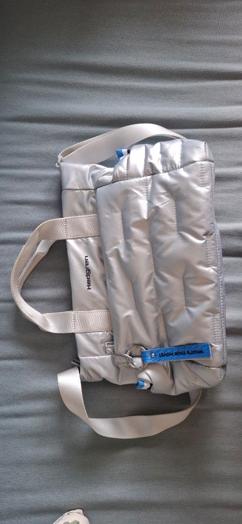 [ HEDGREN ] Silver Puffer Tote Bag with Shoulder Strap (Category: Tote Bags) located in Mandaluyong City. Submitted by crazybaggal (Listing ID 1440498430, Image 2). Description: - Hedgren silver puffer tote bag (used to be limited edition) - Shoulder strap cannot be removed - Comes with a front pouch inside that can be removed via snap closure - Red stain marks on the exterior (bottom of bag) due to proximity from another piece that was dyed red.