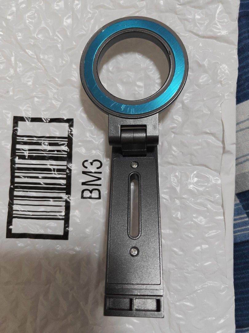 Camera Mount Bracket with Blue Ring (Category: Mounts & Holders) located in Singapore. Submitted by gadgetechno (Listing ID 1440468319, Image 1). Description: - Dark grey camera mount bracket - Features a magnetic ring - Adjustable customization - Sturdy and reliable for phone equipment - Ready for a new owner - I have 2 of these.