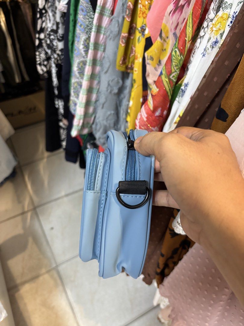 Essentials Fear of God Crossbody Bag Light Blue (Category: Luxury Bags & Wallets) located in Lopez. Submitted by thrift.ni.roms22 (Listing ID 1440511148, Image 2). Description: - Light blue crossbody bag from Essentials - Features 'ESSENTIALS' logo printed on the front - Adjustable black strap with 'ESSENTIALS' branding - Black interior - Original tag included.