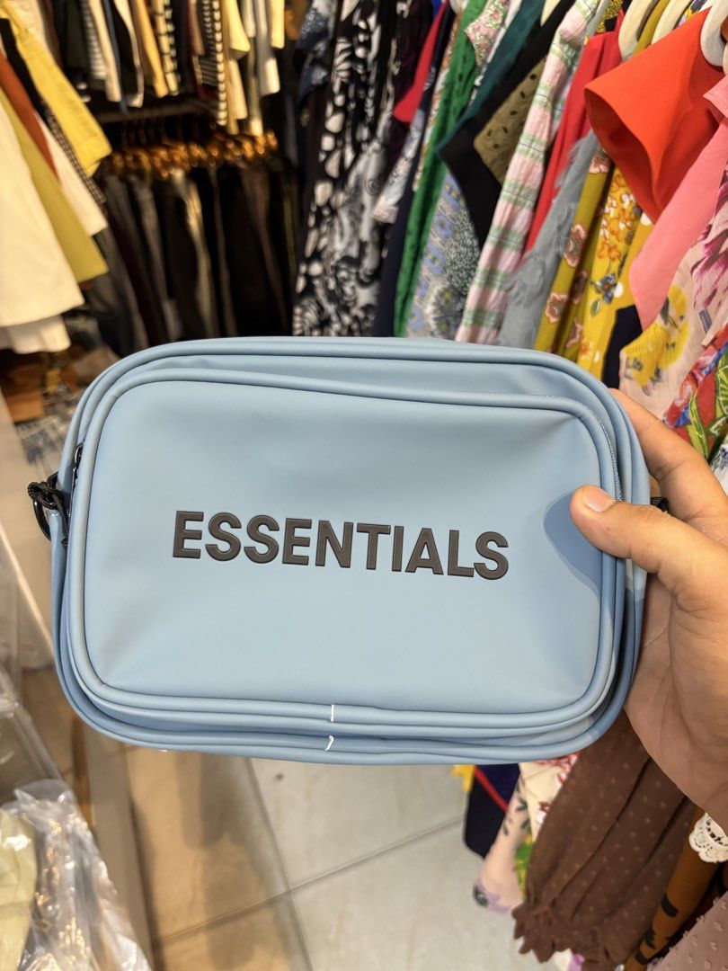 Essentials Fear of God Crossbody Bag Light Blue (Category: Luxury Bags & Wallets) located in Lopez. Submitted by thrift.ni.roms22 (Listing ID 1440511148, Image 1). Description: - Light blue crossbody bag from Essentials - Features 'ESSENTIALS' logo printed on the front - Adjustable black strap with 'ESSENTIALS' branding - Black interior - Original tag included.