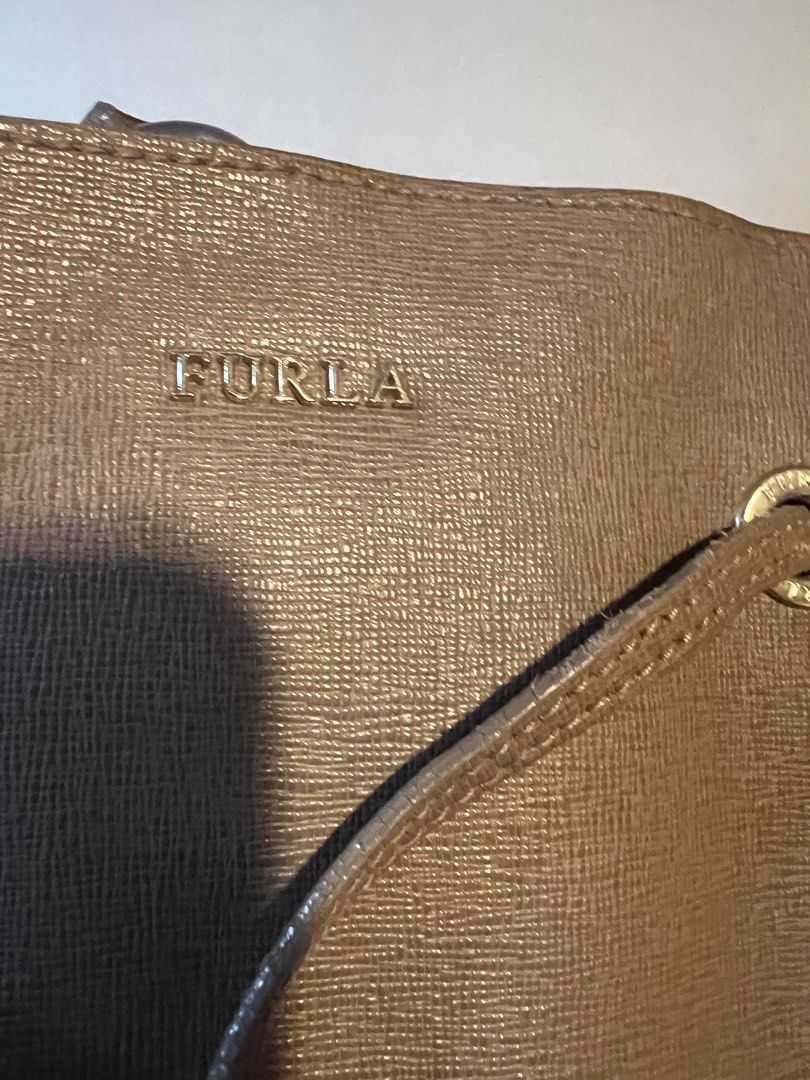 Furla Stacy Medium Drawstring Bucket Bag Leather Taupe (Category: Luxury Bags & Wallets) located in Makati City. Submitted by domingokaye (Listing ID 1440553642, Image 2). Description: - Furla Stacy medium bucket bag - Taupe textured leather - Drawstring closure - Adjustable shoulder strap with gold hardware - Interior with patterned lining - Ideal for everyday use.