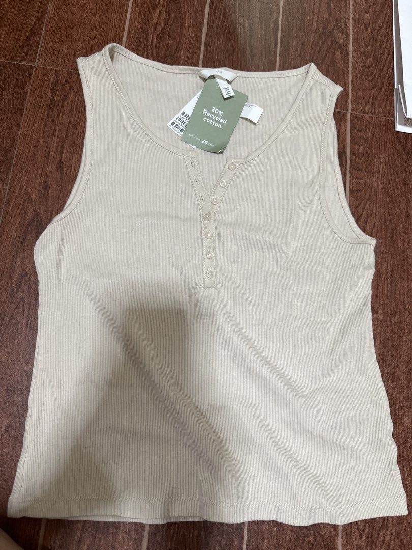 H&M Ribbed Tank Top Beige Size M (Category: Sleeveless) located in Marikina City. Submitted by rctoby00 (Listing ID 1440444932, Image 1). Description: - Cream colored ribbed tank top from H&M - Button-up neckline - Made with 20% recycled cotton - Size Medium - Brand new with tags attached - Perfect basic wardrobe staple.