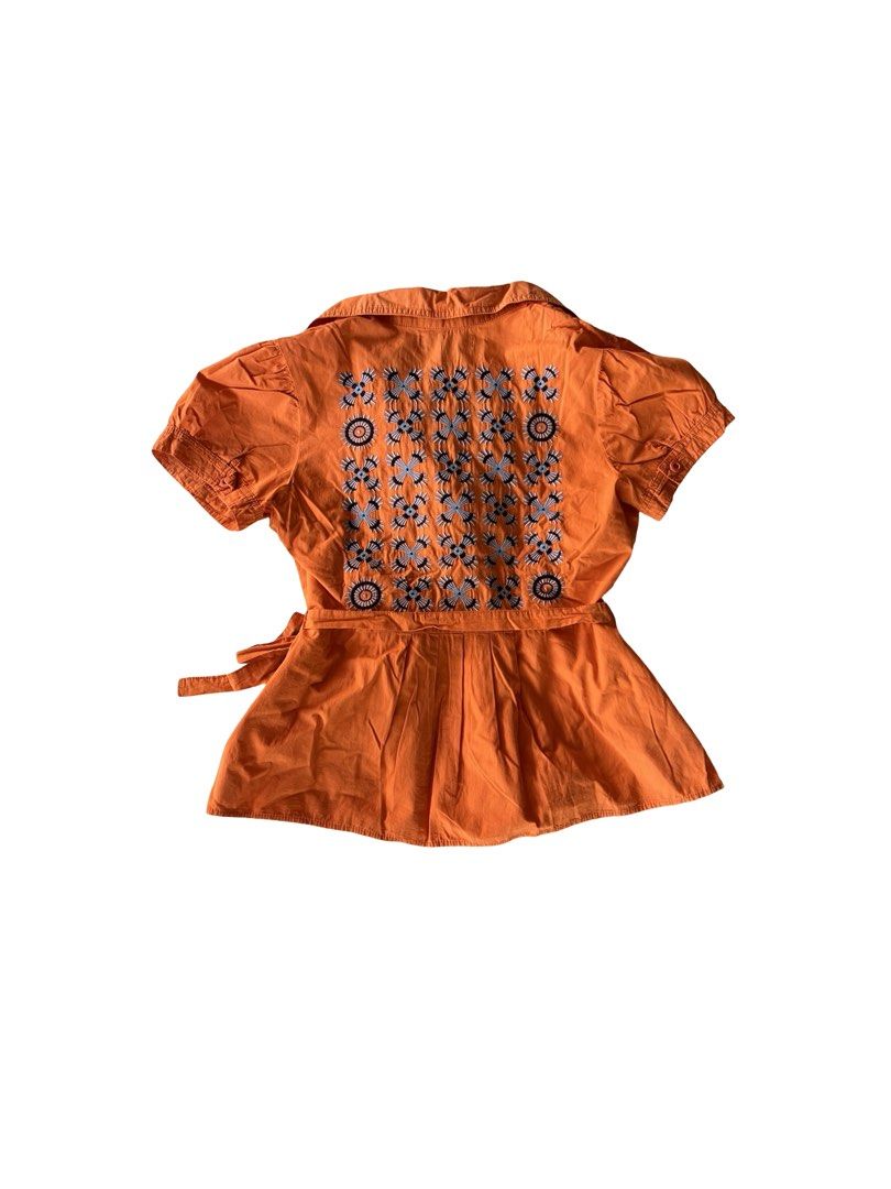 Plains & Prints Wrap Blouse (FREE SHIPPING) (Category: Blouses) located in Jaen. Submitted by relovique_finds.ph (Listing ID 1440386756, Image 2). Description: - Orange wrap blouse from Plains & Prints - Short sleeves and collared neckline - Adjustable tie waist for a flattering fit - Unique blue and grey floral embroidery on the back - Perfect for casual or dressed-up looks.