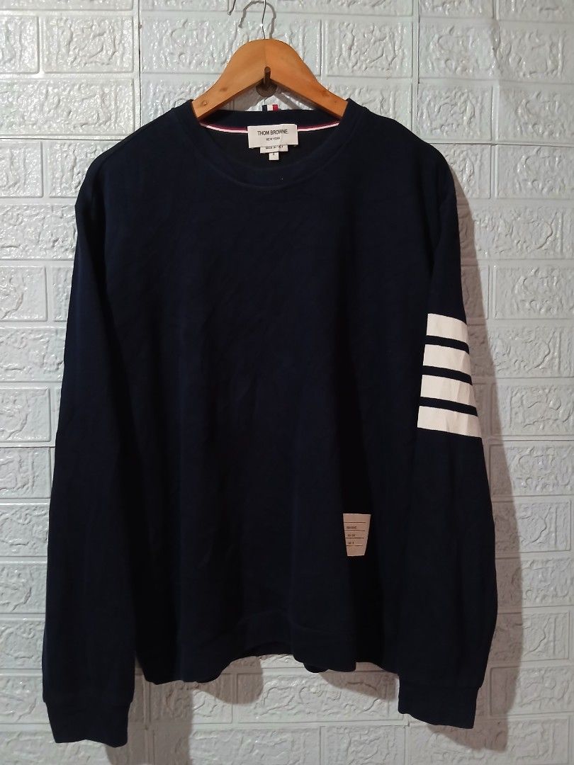 Thom Browne Navy Sweatshirt with White Stripe (Category: Luxury Apparel) located in Davao. Submitted by marissasof29286 (Listing ID 1440452220, Image 1). Description: -Classic Navy Sweatshirt from Thom Browne -Features Signature White Stripes on the sleeve -Small woven label detail -Made in Italy -Perfect for a stylish casual look -Size 4 Large to XL fit -Dimes 22x27 -Color rate 9.5/10 No issue.