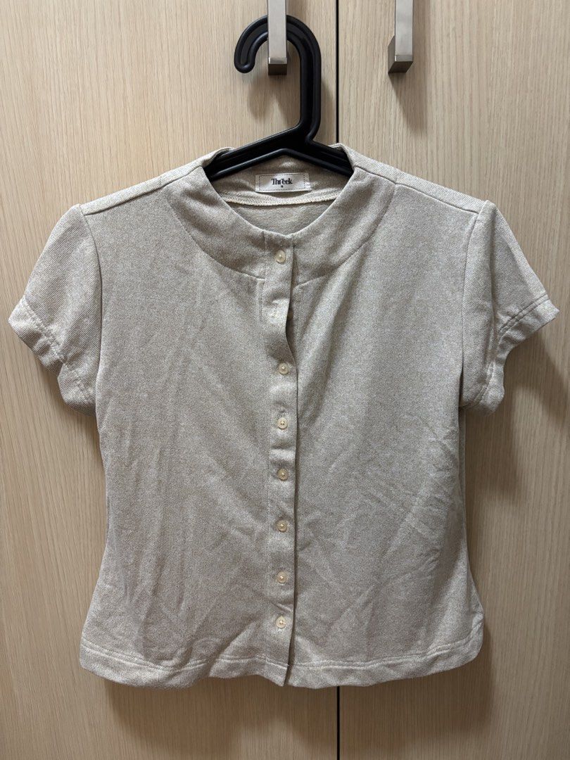 Threek Beige Button-Up Short Sleeve Top Size M (Category: Blouses) located in Pasig City. Submitted by smgss (Listing ID 1440401435, Image 1). Description: - Beige top from Threek - Size: M - Short sleeves - Button-up front - Mandarin collar - Subtle textured fabric - Versatile for casual or dressed-up occasions.