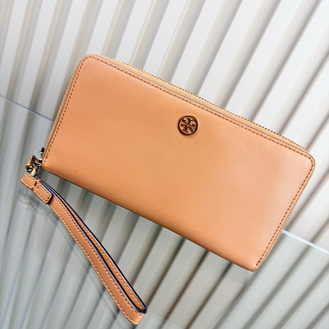 Tory Burch Leather Zip Around Wristlet Wallet (Category: Wallets & Card holders) located in Pasig City. Submitted by trendapparelph (Listing ID 1440433615, Image 2). Description: - Tory Burch zip-around wallet - Genuine tan leather - Detachable wrist strap - Gold hardware - Iconic Tory Burch logo - Spacious interior for cards and cash - Ideal for everyday use or travel - Clean and simple design.
