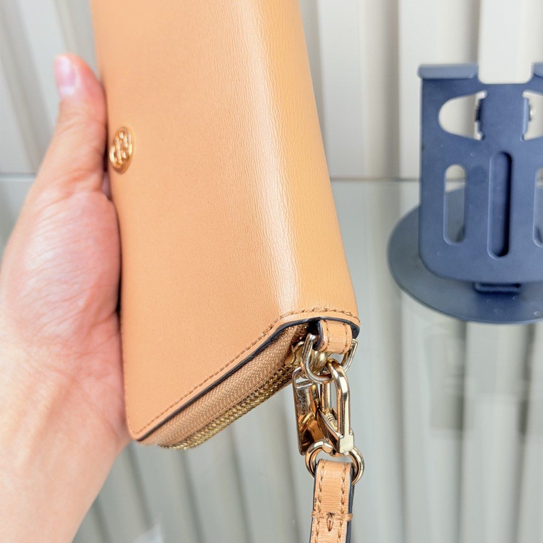 Tory Burch Leather Zip Around Wristlet Wallet (Category: Wallets & Card holders) located in Pasig City. Submitted by trendapparelph (Listing ID 1440433615, Image 3). Description: - Tory Burch zip-around wallet - Genuine tan leather - Detachable wrist strap - Gold hardware - Iconic Tory Burch logo - Spacious interior for cards and cash - Ideal for everyday use or travel - Clean and simple design.