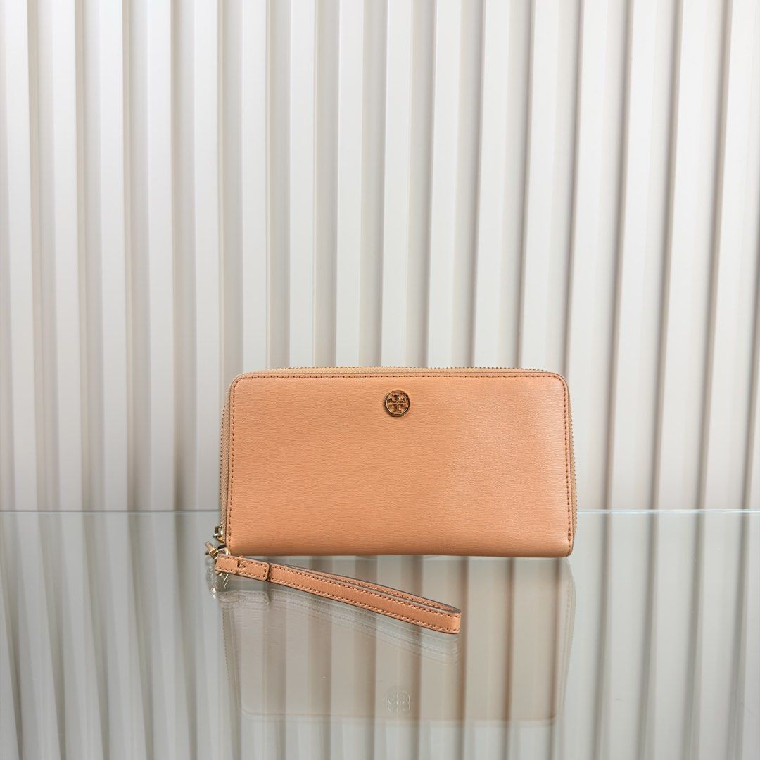 Tory Burch Leather Zip Around Wristlet Wallet (Category: Wallets & Card holders) located in Pasig City. Submitted by trendapparelph (Listing ID 1440433615, Image 1). Description: - Tory Burch zip-around wallet - Genuine tan leather - Detachable wrist strap - Gold hardware - Iconic Tory Burch logo - Spacious interior for cards and cash - Ideal for everyday use or travel - Clean and simple design.