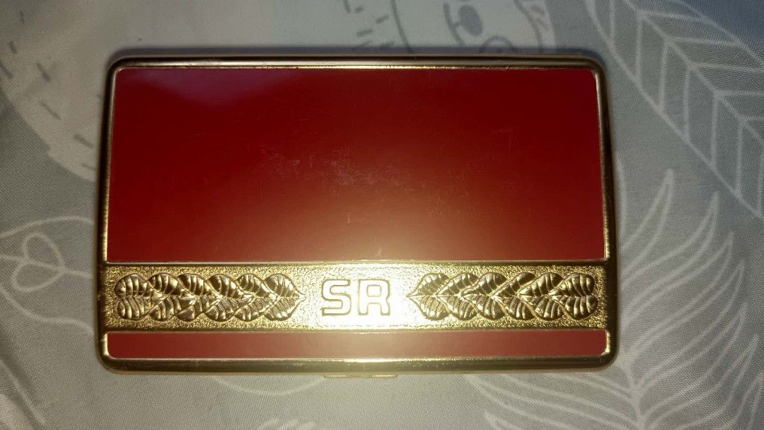 Vintage SR Gold and Red Cigarette Case Holder (Category: Vintage Collectibles) located in Los Banos. Submitted by tritrollse.04 (Listing ID 1440444161, Image 1). Description: - Elegant gold and red cigarette case. - Features a decorative border with 'SR' initials. - Opens to a shiny gold interior. - Includes a strap to keep cigarettes in place. - Secure clasp for safe closure. - A timeless accessory for your cigarettes. -very visible signs of usa