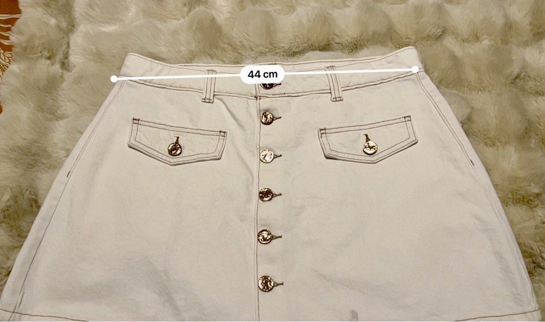 White Button-Front Denim Skirt with Gold Buttons (Category: Skirts) located in Pasig City. Submitted by royalregistry (Listing ID 1440474562, Image 1). Description: - Brandnew. Bought in Australia - Classic white denim skirt - Button-front closure with elegant gold-tone buttons - Two functional front pockets with button closures - One convenient back pocket - Attractive stitching detail throughout - Measurements: Waist 44cm, Length 38cm.
