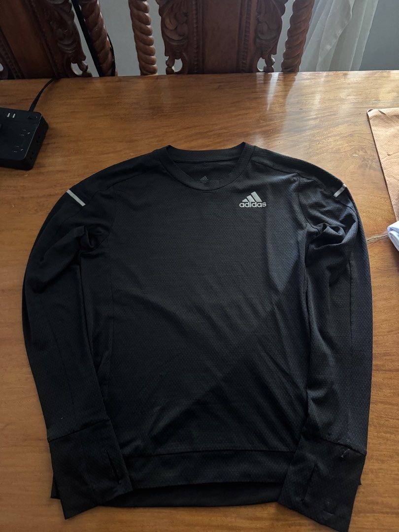 Adidas Long Sleeve Running Shirt (Category: Activewear) located in Bacoor. Submitted by hello.curated (Listing ID 1440605365, Image 1). Description: - Black Adidas long-sleeved shirt - Features thumbholes on sleeves for extra coverage - Reflective details on shoulders - Ideal for running or workouts - Made with lightweight and breathable material.