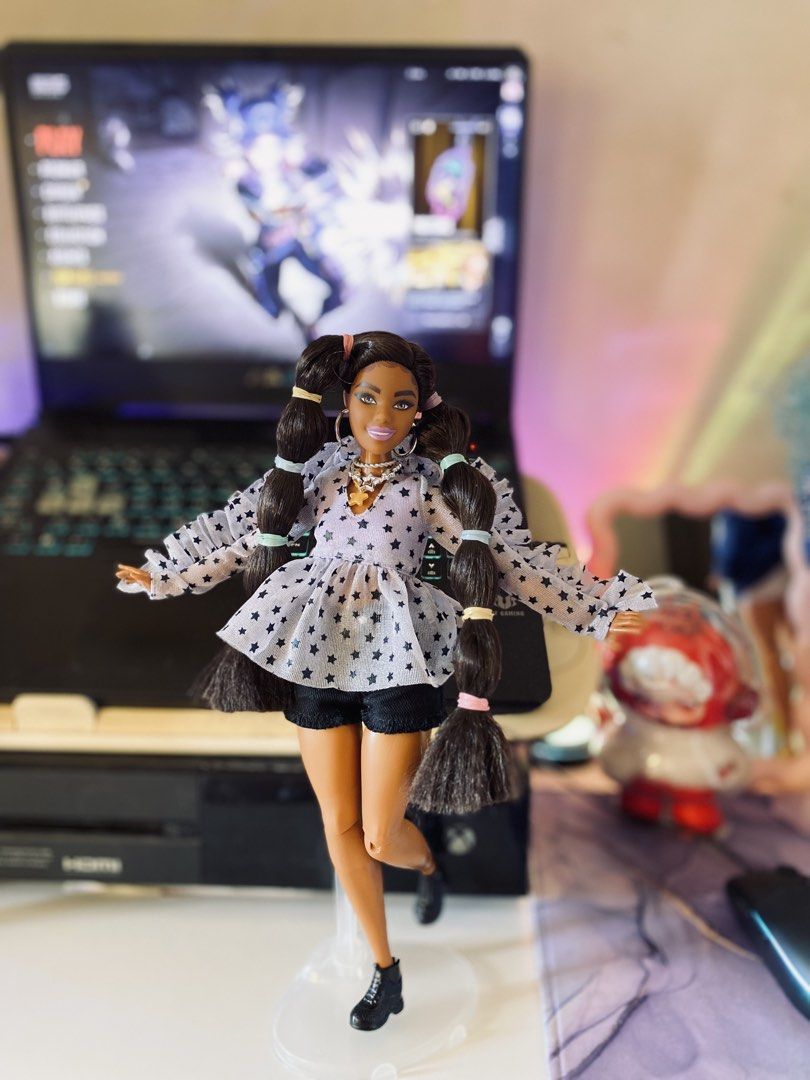 Barbie Extra #7 (Category: Kids Toys) located in Quezon City. Submitted by micah0920 (Listing ID 1440723369, Image 1). Description: - Barbie doll with long dark hair in pigtails. - Features a star-print top with ruffled sleeves. - Wears black shorts. - Accessories: hoop earrings and star pendant necklace. - Ideal for collectors and playtime..