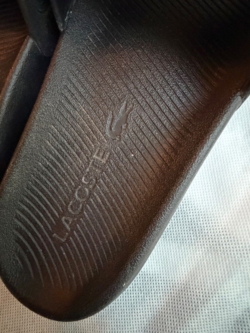 Black Lacoste Slides with Gold Crocodile Logo (Category: Slippers & Slides) located in Manila. Submitted by mypersonalclothes (Listing ID 1440734723, Image 3). Description: - Classic black Lacoste slides - Features iconic gold crocodile logo on the strap - Textured footbed with embossed Lacoste name for grip - Easy slip-on design - Ideal for casual wear or after sports.