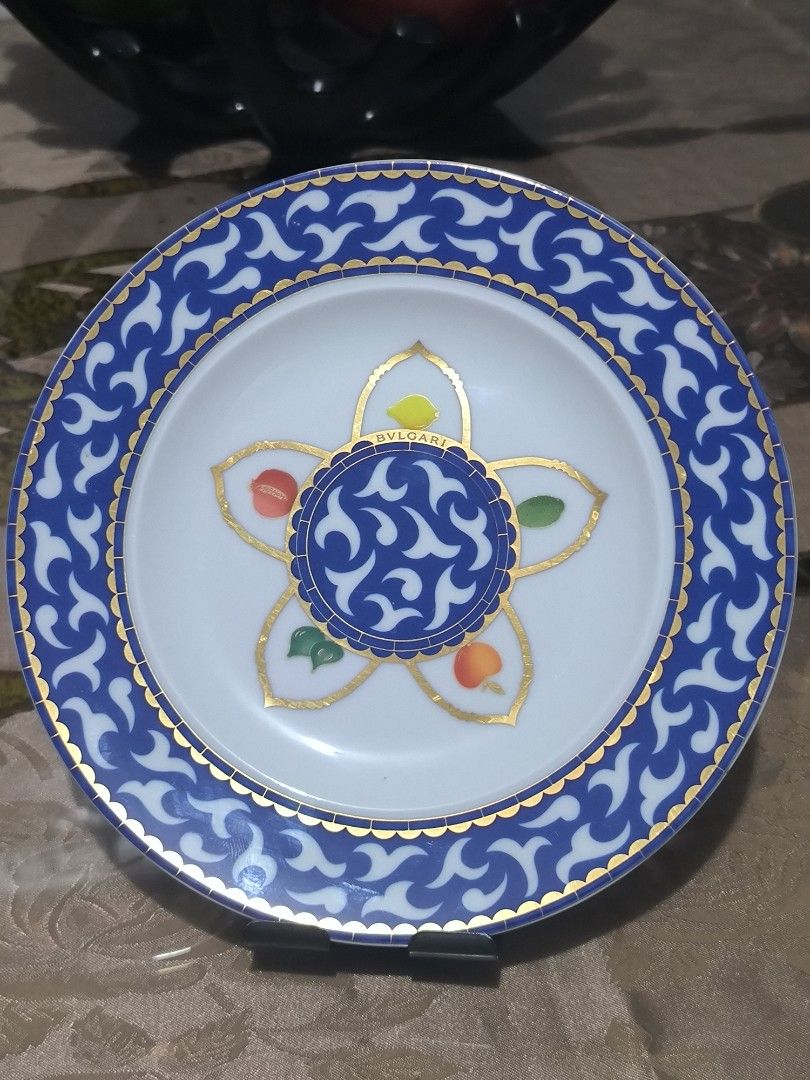 Bulgari Frutta ala Finestra (Category: Dinnerware & Cutlery) located in Bulacan. Submitted by tripledouble532 (Listing ID 1440630303, Image 1). Description: This is a BVLGARI "Frutta alla Finestra" porcelain plate produced in collaboration with Rosenthal. Design Details: The plate features a central motif of blue and white swirling patterns surrounded by stylized fruit designs and gold accents. Dimensions: Sizes available in this pattern range fr